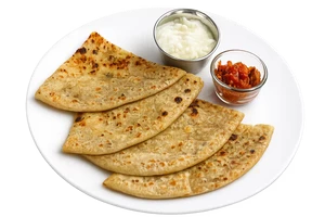Four triangular flatbreads or parathas made with Milld high protein atta arranged on a white plate, served with a small bowl of white chutney and a small bowl of red chutney on a white background.
